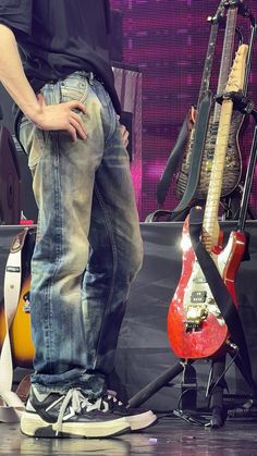 a man standing on top of a stage next to guitars