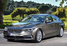 the new bmw 7 series sedan is parked in front of some trees and green grass