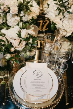 an elegant table setting with white flowers and gold place settings for the guests to sit at