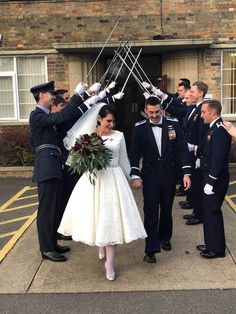 a bride and groom walking down the street with their wedding party in front of them