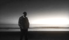 a man standing on top of a beach next to the ocean