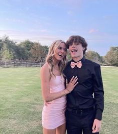 a man in a tuxedo poses with a woman in a pink dress