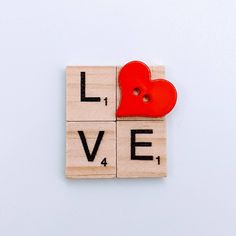 the word love spelled with scrabbles and a red heart on a white background