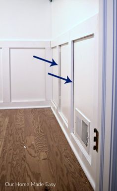 an empty room with white walls and wood flooring that has blue arrows pointing in opposite directions