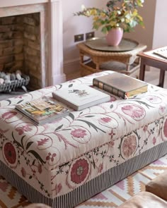 a living room filled with furniture and a fire place covered in books on top of a ottoman