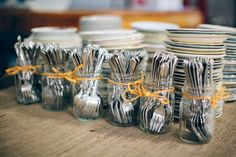 there are many empty glass jars with forks and spoons in them on the table