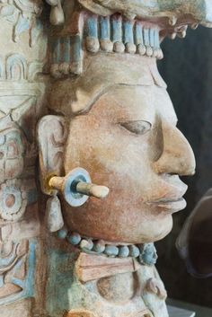 a close up of a statue with an object in it's mouth and head