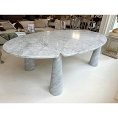 a large white marble dining table in a living room with chairs and couches behind it