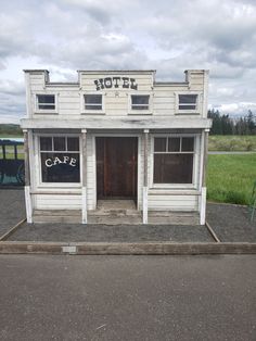 an old white building sitting on the side of a road