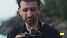 a man holding a camera in front of his face and looking into the camera lens