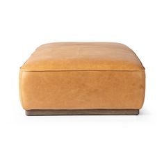 a tan leather ottoman sitting on top of a white floor