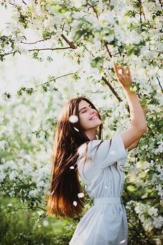 a woman standing under a tree with her hair blowing in the wind