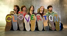 five men sitting in front of the word love written on their shoes, all lined up