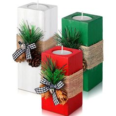 two christmas candles sitting next to each other with pine cones on the front and one in the back