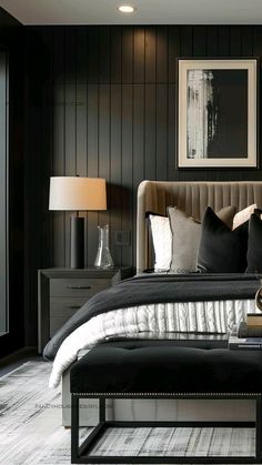 a bedroom with black and white bedding, pillows and pictures on the wall above it