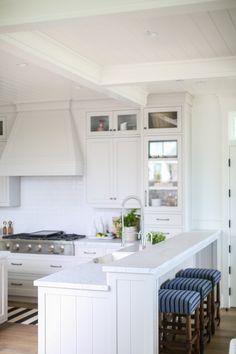 a kitchen with white cabinets and an island in the middle, along with blue stools