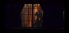 the silhouette of a person standing in front of a window with curtains on it, at night