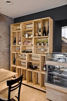 a wooden shelf filled with lots of bottles next to a dining room table and chairs