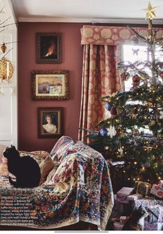 a living room with a christmas tree in the corner and a cat on the couch