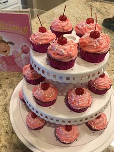 cupcakes with pink frosting and cherries are stacked on top of each other