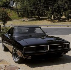 a black muscle car parked in front of a house