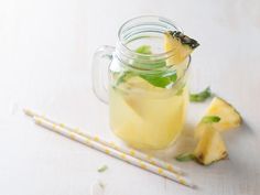 a mason jar filled with pineapple and mint tea next to two yellow straws