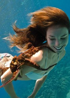 a woman is swimming under the water with her hair blowing in the wind and smiling