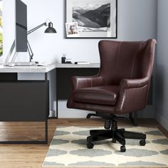 a brown leather office chair sitting in front of a computer desk