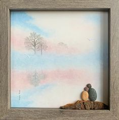 a painting in a wooden frame with two rocks and a tree on the other side