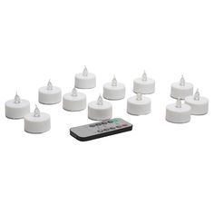 there are many white candles and remotes next to each other on a white surface