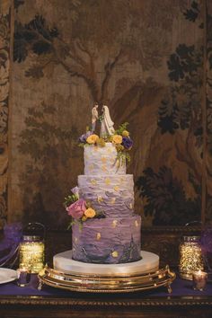 a wedding cake with purple frosting and yellow flowers on the top is surrounded by candles