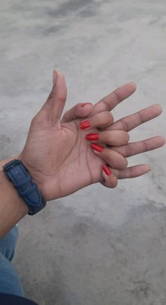 a woman's hand with red nail polish holding out her left hand to the camera