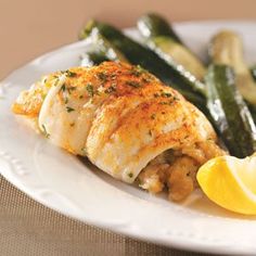 a white plate topped with fish, asparagus and lemon wedges next to green beans