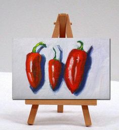 a painting of three red peppers on an easel