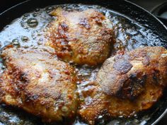 three pieces of meat cooking in a skillet