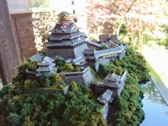 a model of a building with trees and bushes on the top floor in front of it