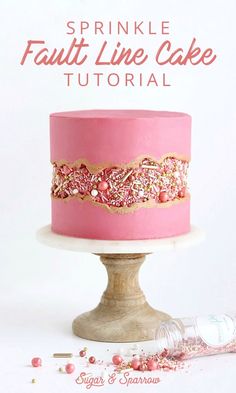 a pink cake with sprinkles on it sitting on top of a table