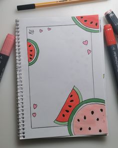 an open notebook with watermelon and hearts on it next to markers, pencils and marker pens