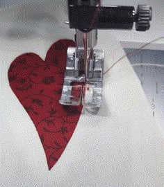 a sewing machine with a red heart on it's side next to a piece of fabric