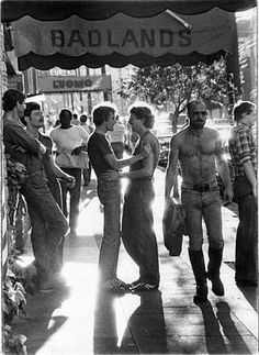 black and white photograph of men standing under an awning with badland's sign in the background