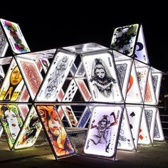 an art installation made out of playing cards at night with lights in the shape of pyramids