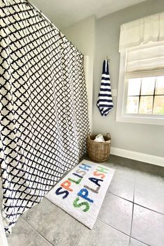 a bathroom with a black and white shower curtain next to a rug on the floor