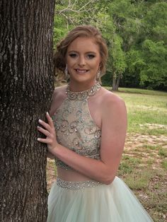 a woman in a dress standing next to a tree