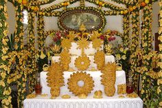 a white and yellow wedding cake sitting on top of a table covered in fake flowers