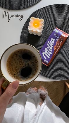 a person holding a cup of coffee next to a chocolate bar