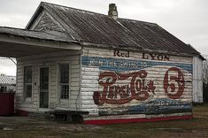 an old coca - cola building is painted white with red and blue lettering on it