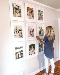 a woman standing in front of a wall with pictures on it