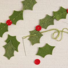 the holly garland is made from felt and has red buttons on it, as well as green leaves