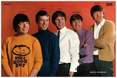 an old photo of four men in sweaters and one is smiling at the camera