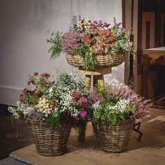 three baskets filled with flowers sitting on top of a wooden table